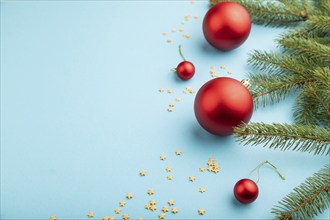 Christmas or New Year composition. Decorations, red balls, fir and spruce branches, on a blue paper