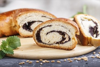 Homemade yeast rolls with poppy seeds and honey on a wooden kitchen board on a black concrete