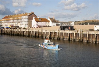 Small fishing boat leaving the harbour at West Bay, Bridport, Dorset, England, UK