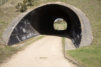 View through tunnel lined by corrugated iron with light at the end