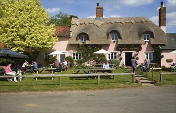 People sitting outside the Sorrel Horse thatched village pub, Shottisham, Suffolk, England, United