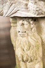 Stone carved lion animal figure support on baptismal font in village parish church, Saint John the