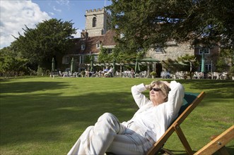 Woman sunbathing in gardens of the Priory Hotel, Wareham, Dorset, England, UK