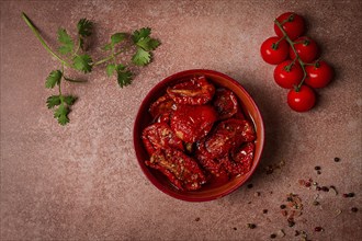 Dried tomatoes, in a bowl, top view, on a brown background