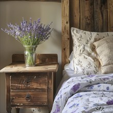 Lavender flowers (Lavendula) in a vase on a bedside table next to a bed, rustic, rural ambience, AI