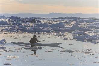 Inuit paddling a kayak between icebergs, man, sunny, summer, Ilulissat, Ilulissat Icefjord, Disko