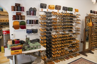 A shoe shop with a large selection of sandals and leather bags, neatly displayed on shelves,