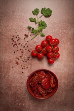 Dried tomatoes, in a bowl, top view, on a brown background