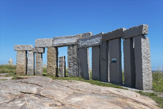 Circular stone structure, standing under a clear blue sky with nature in the background, Monumento