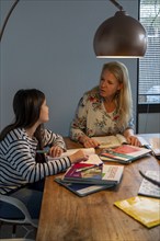 Homeschooling, during the lockdown in January 2021, mother helps her two daughters, at home,