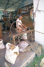 Indian worker winding coils in the Labourers Coir Mats and Mattings Cooperation, coir mat