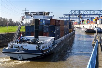 Container cargo ship enters the port basin of the Logport, gantry cranes in the Container Handling