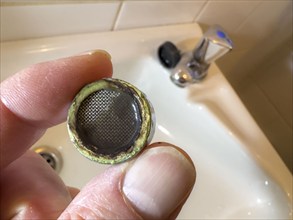 Calcified, clogged faucet aerator, limescale residue clogs the strainer of the faucet aerator