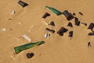 Broken glass bottles and rubbish on sand showing pollution in a desert, Matruh, Great Sand Sea,