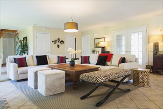 Beige upholstered sofas with colourful cushions, wooden coffee table and zebra motif ottoman in