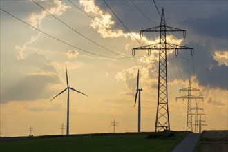 Wind farm, wind turbine, wind turbines, in front of sunset, thunderclouds, overhead power lines,