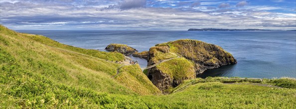 Panoramic view of green hills and the coast with a suspension bridge and deep blue sea, Carrick