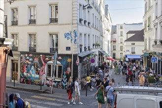 Lively street scene with graffiti and people enjoying the atmosphere, Paris