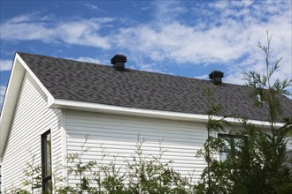 White clapboard cladded two story home with light and dark grey nuanced asphalt shingles roof