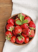 Fresh red strawberry in wooden bowl on wooden background. top view, flat lay, close up