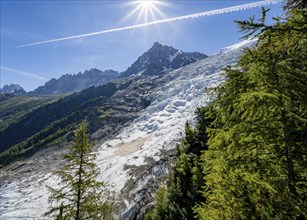 View of glacier Glacier des Bossons with sun star, behind summit of Aiguille du Midi, Chamonix,