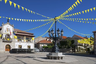 Municipal square with old street lamps, a historic building and festive yellow flags under a clear