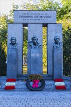 Monument to the Republic, decorated with a wreath of honour and red and white flowers, behind the