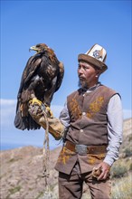 Traditional Kyrgyz eagle hunter with eagle in the mountains, near Kysyl-Suu, Kyrgyzstan, Asia