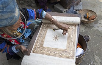 Vietnamese woman from the Hmong minority draws a pattern on linen fabric, Lung Tam linen weaving