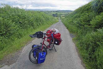 Travelling by bike with full luggage on a small road in the countryside, cycle tour, Highlands,