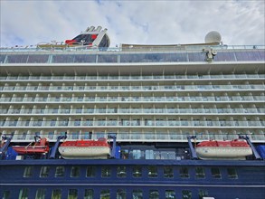 Side view of a large cruise ship Mein Schiff 6, with several decks and attached lifeboats under a