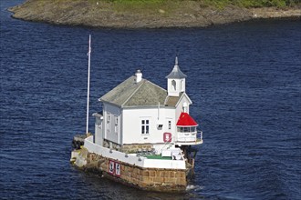 A lighthouse standing on a rock in the sea, with deep blue water and tranquil surroundings,