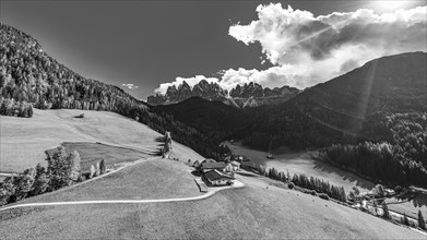 Farm and alpine meadows, in the background the peaks of the Geisler group, drone shot, black and