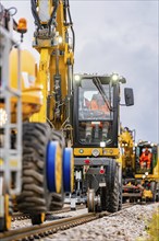 Vehicles and workers working closely together on a railway line with machines, track construction