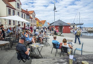 People at outdoor cafe by the harbor in Gudhjem, Denmark, Baltic Sea, Scandinavia, Europe