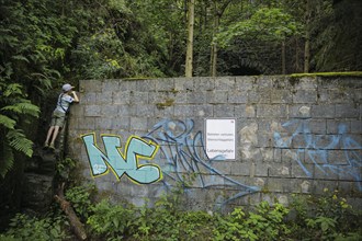 Symbolic photo on the subject of curiosity in children. A boy stands on a stone and looks over a