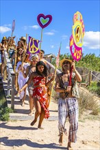 Colourfully dressed youths with musical instruments and banners form a love parade and promote the