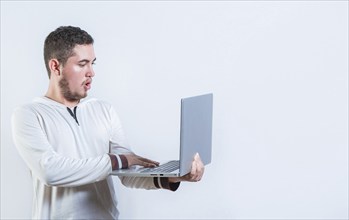 Surprised guy holding and looking at an promotion on laptop screen. Amazed handsome man standing