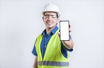 Smiling engineer showing cell phone screen isolated. Young construction engineer showing an