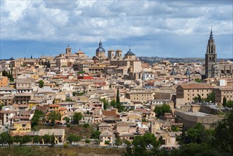 View of the city of Toledo with historical buildings and a cathedral under a cloudy sky, on the