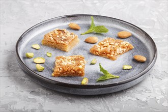 Traditional arabic sweets in gray ceramic plate on a gray concrete background. side view, close up