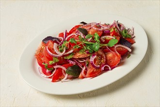 Fresh tomato salad, with red onion, spices and herbs, top view, close-up, homemade