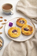 Small cheesecakes with jam and almonds with cup of coffee on a white concrete background and linen