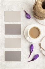 Gray paper business card mockup with spring snowdrop crocus flowers and cup of coffee on gray