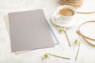 Gray paper sheet mockup with spring snowdrop galanthus flowers and cup of coffee on gray concrete