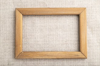 Wooden frame on smooth linen tissue. Top view, flat lay, natural textile background and texture