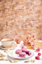 Purple macarons or macaroons cakes with cup of coffee on a white and brown concrete background