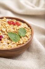 Wheat flakes porridge with milk, raspberry and currant in wooden bowl on white wooden background