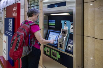 Interior shot, elderly woman, best ager at ticket machine, ticket terminal, Al Ras Station, train