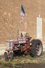 Detroit, Michigan, An old McCormick Farmall tractor flies a tattered American flag outside an auto